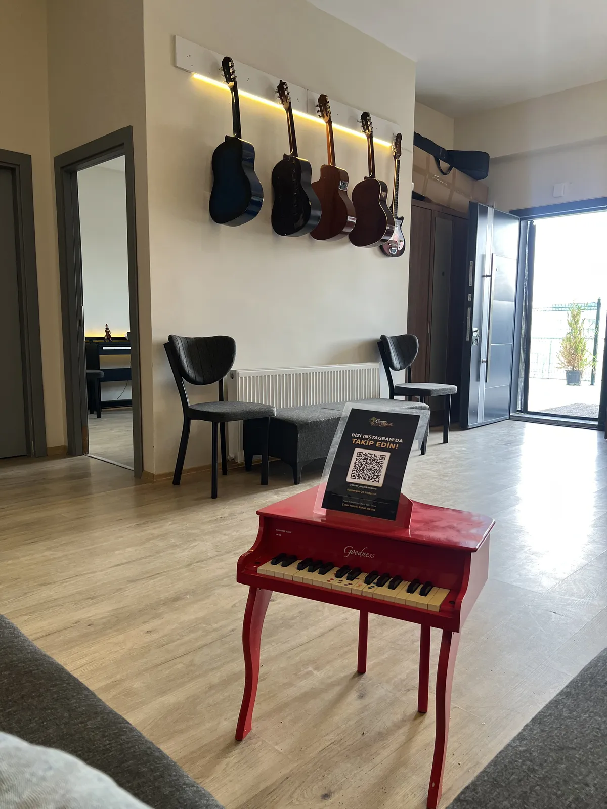 Kırmızı minyatür piyano ve duvarda asılı gitarlar